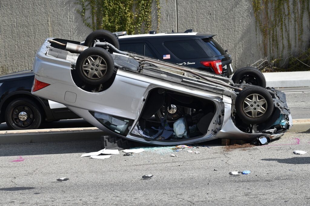 Image shows afermath of a serious car accident with the vehicle flipped upside down on a road in the United States.